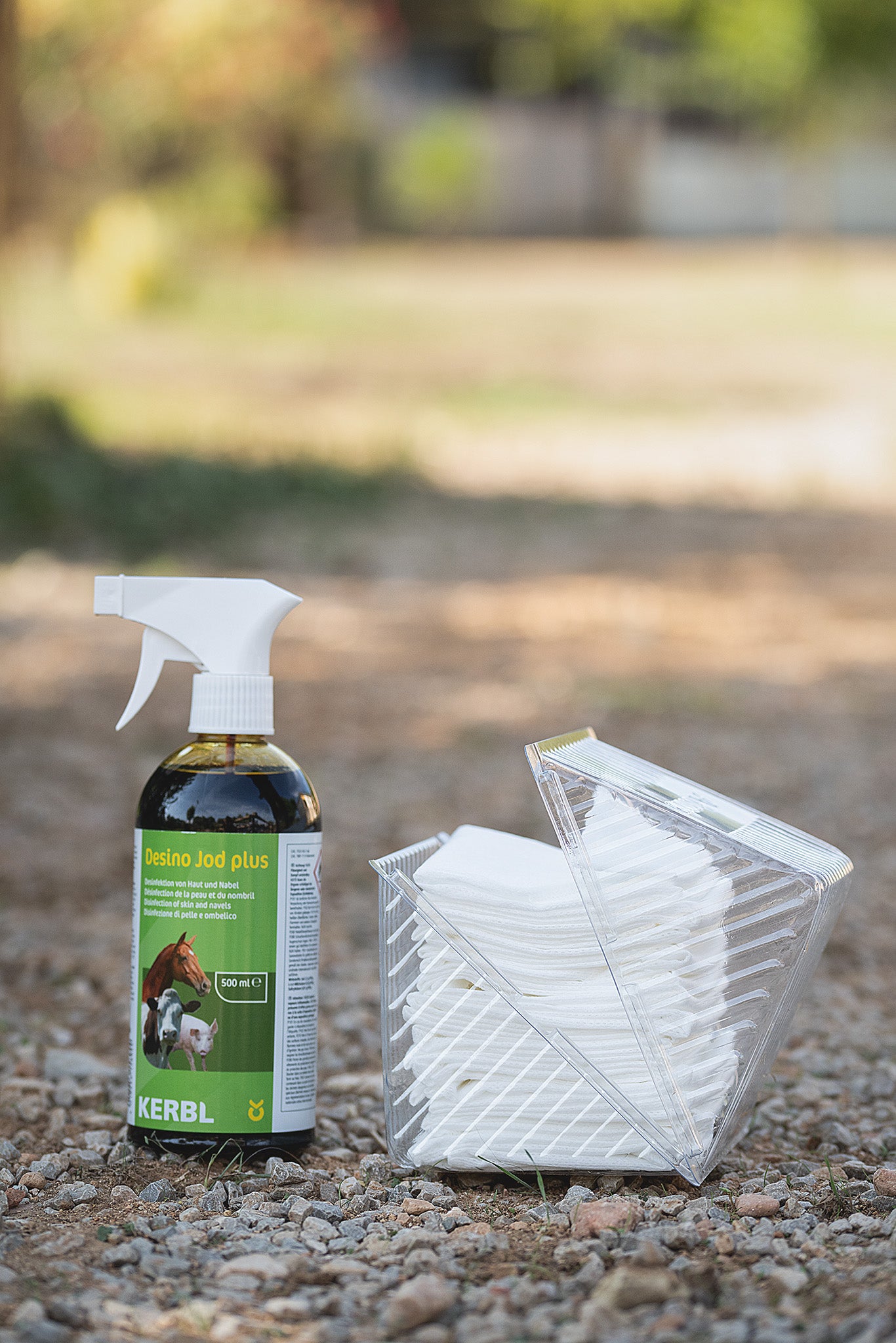 Kerbl Absorba Verbandvlies 10 cm x 5 m liegt in der Natur, daneben steht Desino Jodspray von Kerbl