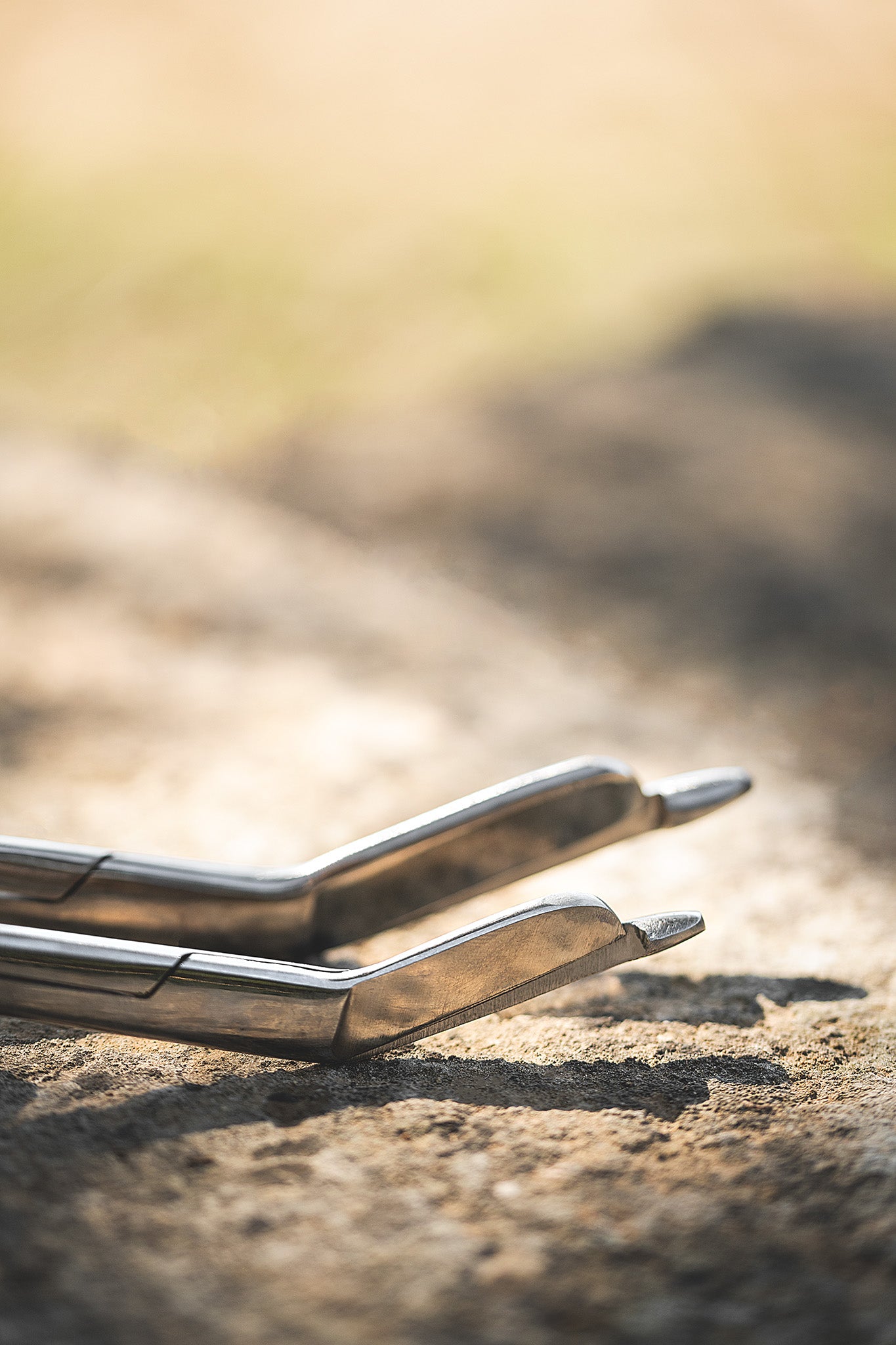 Zwei Kerbl Verbandsscheren aus Edelstahl mit abgerundeter Spitze liegen auf einem Stein im Sonnenlicht