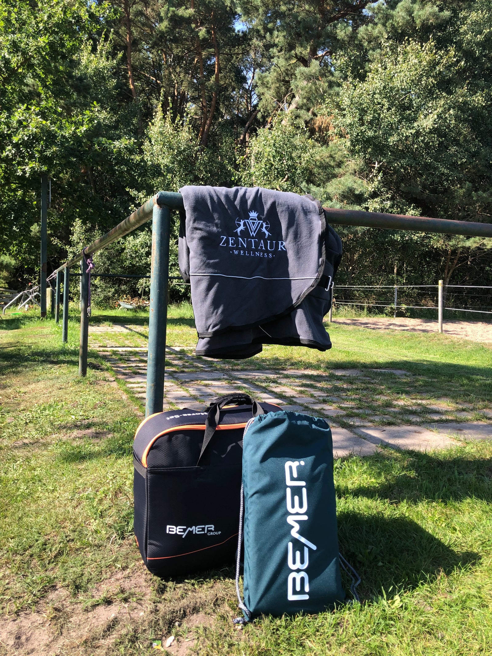 Bemer Horse Set auf einer Koppel: Abschwitzdecke hängt auf Geländer - Pferdedecke, Gamaschen und Zubehör sind in praktischer Bemer Tasche verstaut.