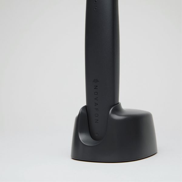 Nahaufnahme des schwarzen Novafon Power in der passenden Ladestation – elegantes Schallwellengerät für gezielte Tiefenstimulation und Regeneration