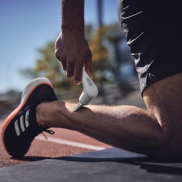 Novafon Physio-Set – Anwendung des weißen Keilaufsatzes zur Faszienbehandlung und Muskelentspannung an der Wade eines Sportlers