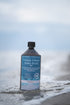 Totes Meer Salzsole 5% naturrein und ohne Zusatzstoffe - Flasche vor Meereskulisse im Wasser stehend